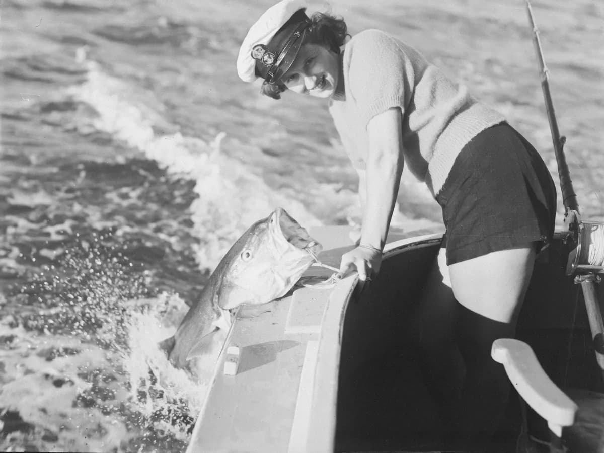 Woman smiling on a deep sea fishing charter holding a large fish
